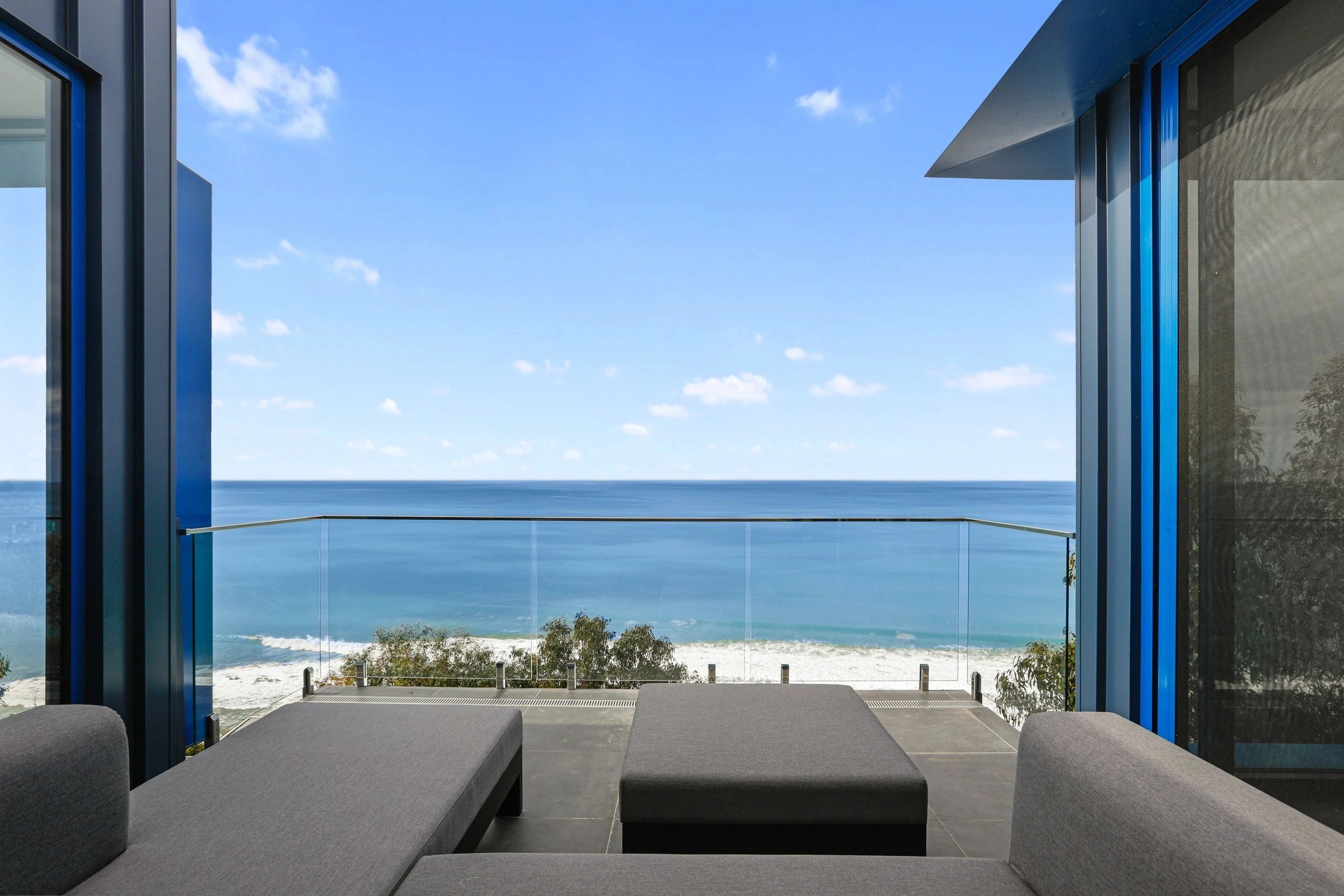 Ocean views through the blue-framed doors at WyeSass, with lounge seating opening onto the balcony